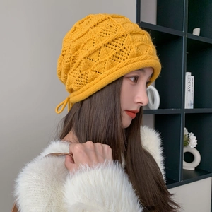 Dettaglio berretto giallo in maglia traforata con lacci laterali decorativi