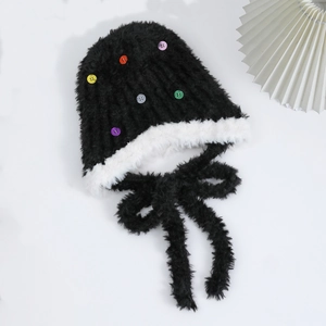 Dettaglio del cappello di peluche nero con bottoni colorati e bordo in ecopelliccia