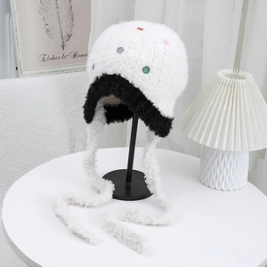 Dettaglio del cappello di peluche con paraorecchie in pelliccia sintetica bianca e nera e bottoni