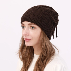 Detail of dark brown cable knit slouchy beanie with adjustable drawstring and metal charm
