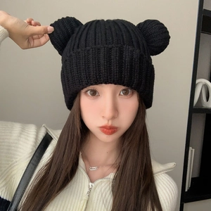 Close-up detail of soft black knitted beanie with cute bear ears and ribbed texture