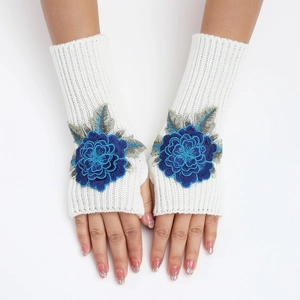 Détail de mitaines en tricot blanc avec broderies florales bleues et texture à côtes
