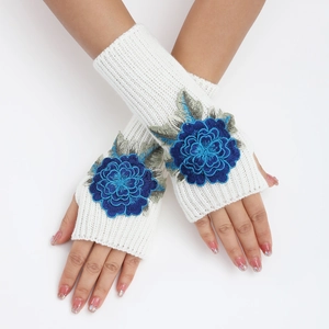 Détail de mitaines en tricot blanc avec broderie florale bleue 3D et texture côtelée