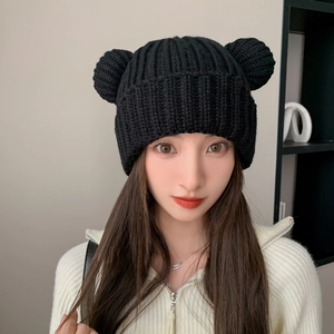 Detailed close-up of a black knitted beanie with cute bear ears and soft texture