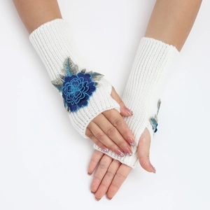 Détail de mitaines en tricot blanc côtelé avec broderie florale bleue élégante