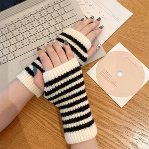 Close-up of black and white striped knit fingerless gloves on a wooden desk with a laptop