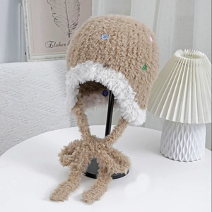 Dettaglio del berretto di peluche marrone con bottoni colorati e bordo in ecopelliccia