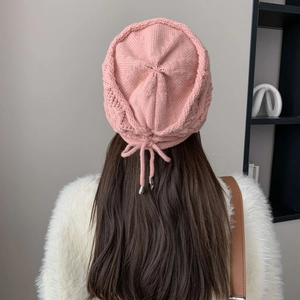 Dettaglio del retro di un berretto in maglia con fiocco rosa e punte in metallo