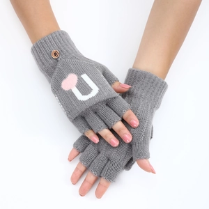 Détail de gants tricotés gris avec lettre U blanche, cœur rose et petit bouton