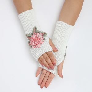 Détail des mitaines blanches tricotées avec broderies florales roses et bords côtelés