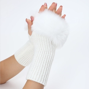 Detalle de guantes de punto blancos sin dedos con un pompón de piel sintética suave