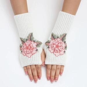 Détail de mitaines en tricot blanc crème avec broderie florale rose et feuilles vertes