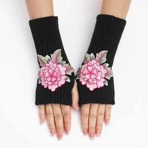 Détail de mitaines en tricot noir avec broderie 3D de pivoine rose et feuilles vertes