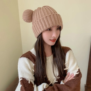 Detail of cute bear ear pom-poms on a warm khaki knit beanie with ribbed texture