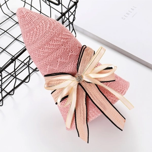 Detail of pink knitted sun hat with a decorative ribbon bow and heart-shaped rhinestone
