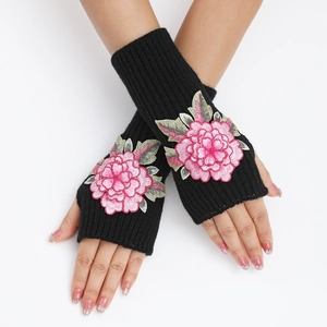 Détail de mitaines en tricot noir avec broderie florale rose et finitions à bords-côtes