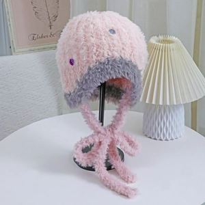 Dettaglio del cappello in peluche rosa e grigio con lunghi cinturini in ecopelliccia