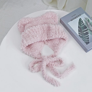 Detail of pink plush cat ear hat with long tassels on a minimalist aesthetic background