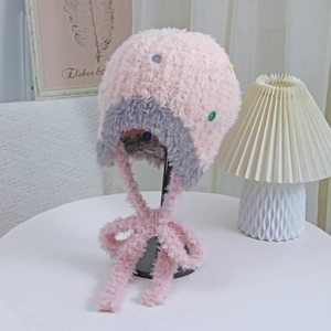 Dettaglio del cappello in peluche con paraorecchie, bottoni colorati e filato rosa