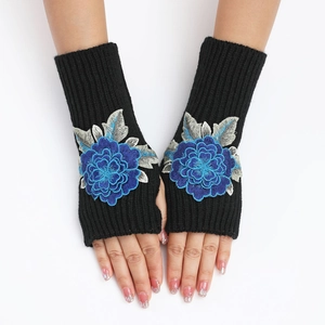 Détail de mitaines noires en maille côtelée avec broderie florale bleue en relief dessus
