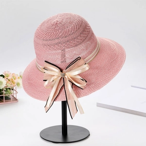 Close-up of pink woven sun hat featuring a large bow with heart-shaped crystal on a stand