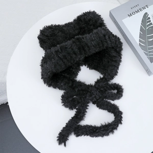 Detailed view of plush black faux fur ties on a warm winter hat over a white platform