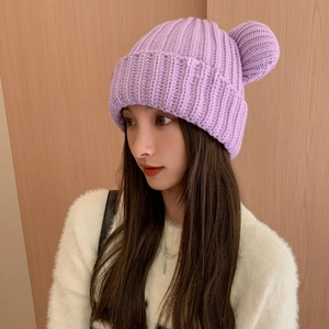 Close-up of thick light purple knitted hat with pompom and wide ribbed cuff detail