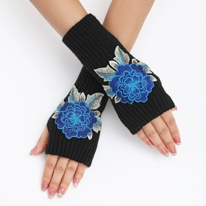 Détail de mitaines noires en maille côtelée avec broderie florale bleue sur les mains