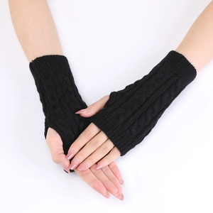 Detail of black cable knit arm warmers with thumb holes and textured wool blend pattern