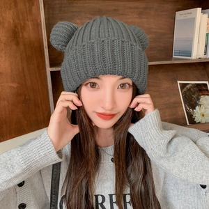 Detail of grey knitted beanie with cute bear ears and thick texture on a female model