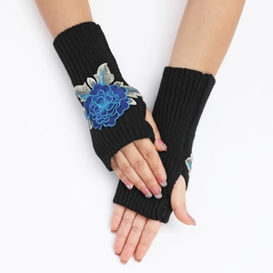 Détail de mitaines noires en tricot avec broderie fleur bleue 3D et poignets côtelés