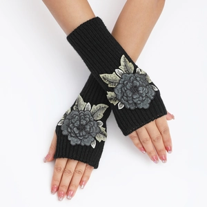 Détail de mitaines en tricot noir avec élégants patchs de fleurs brodées sur le dessus