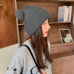 Close-up of dark grey knit hat with cute bear ears worn by model in warm cozy studio