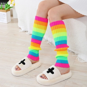Close-up of rainbow striped knit leg warmers paired with plush cross motif slippers