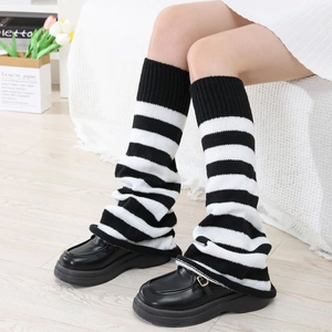 Detailed knit texture of black and white striped leg warmers worn with loafers