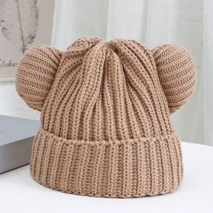 Close-up of thick ribbed knit texture and cute bear ear design on a warm beige beanie