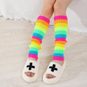 Detail of colorful rainbow striped knit leg warmers paired with white plush slippers