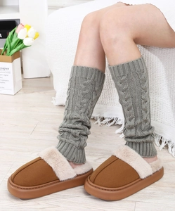 Macro shot of grey cable knit leg warmers paired with brown platform fur-lined slippers