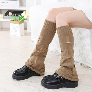 Nahaufnahme brauner Strickstulpen im Distressed-Look mit schwarzen Leder-Loafern