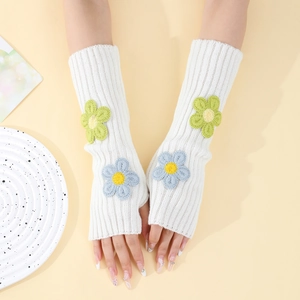 Detailed knit texture of white fingerless arm warmers with crochet flower patches