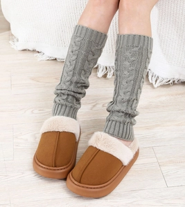 Close-up of grey cable knit leg warmers paired with warm brown suede slippers