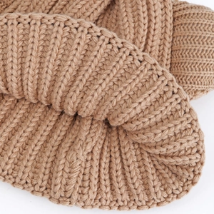 Close-up of thick camel knit texture with ribbed patterns on a winter beanie hat