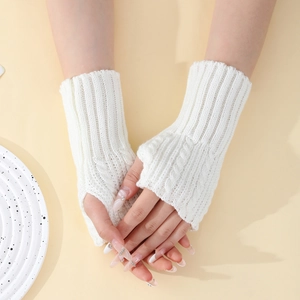 Détail de gants en maille torsadée blanche montrant la texture douce et les bords-côtes