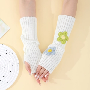 Detail of white rib-knit fingerless arm warmers featuring blue and green crochet flowers