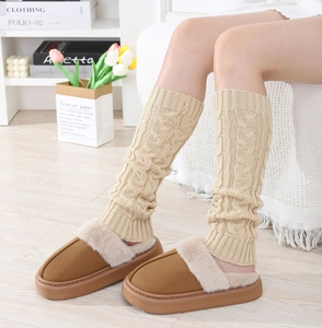 Detail of chunky beige cable knit leg warmers paired with plush brown fur-lined slippers