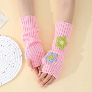 Detail of pink knitted arm warmers with embroidered flower decor and thumb hole