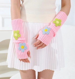 Close-up of pink knit fingerless gloves with crochet flower detail and ribbed texture