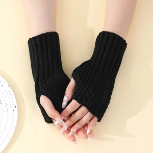 Détail de la texture en tricot torsadé noir des mitaines avec trou pour le pouce