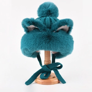 Detail of teal knit winter hat featuring plush cat ears, fluffy pompom and faux fur lining