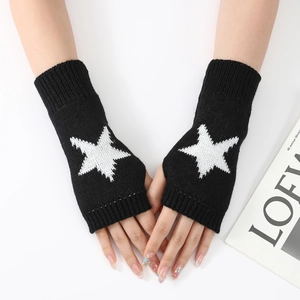 Détail de mitaines en tricot noir avec un motif d'étoile pentagramme blanc et bords côtelés